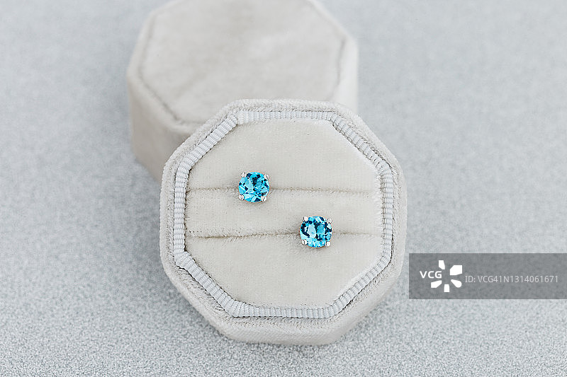 白色珠宝盒中的蓝色托帕石耳钉图片素材