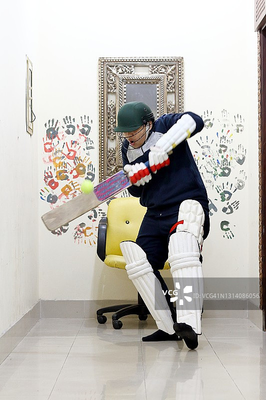 小男孩在家中打板球图片素材