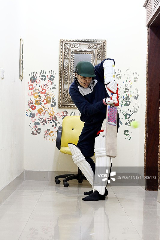 小男孩在家中打板球图片素材