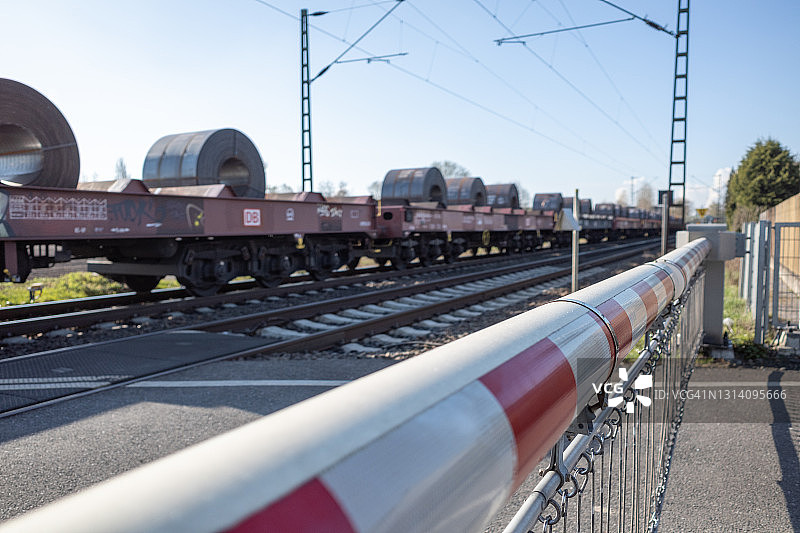 红白相间的铁路道口栏杆，阻挡道路和货运列车图片素材
