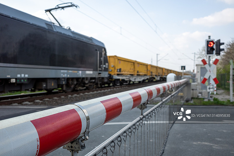 红白相间的铁路道口栏杆，阻挡道路和货运列车图片素材