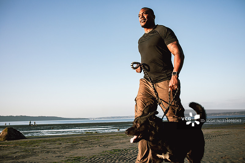 成年男人和忠犬在海滩上图片素材