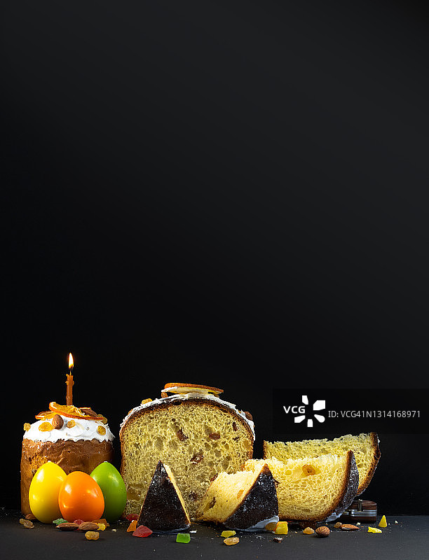 黑色背景上的传统复活节蛋糕，蜜饯水果，葡萄干，彩色鸡蛋装饰，燃烧的蜡烛，东正教美食，垂直照片图片素材