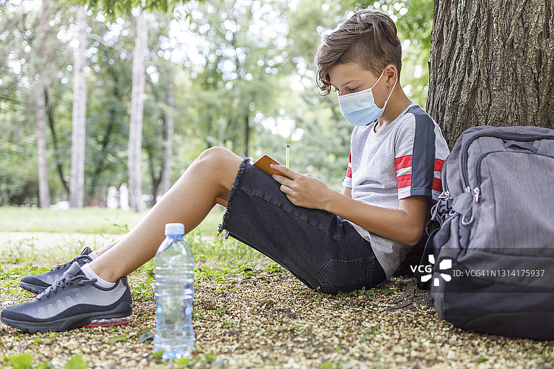 戴口罩在户外学习的男学生图片素材
