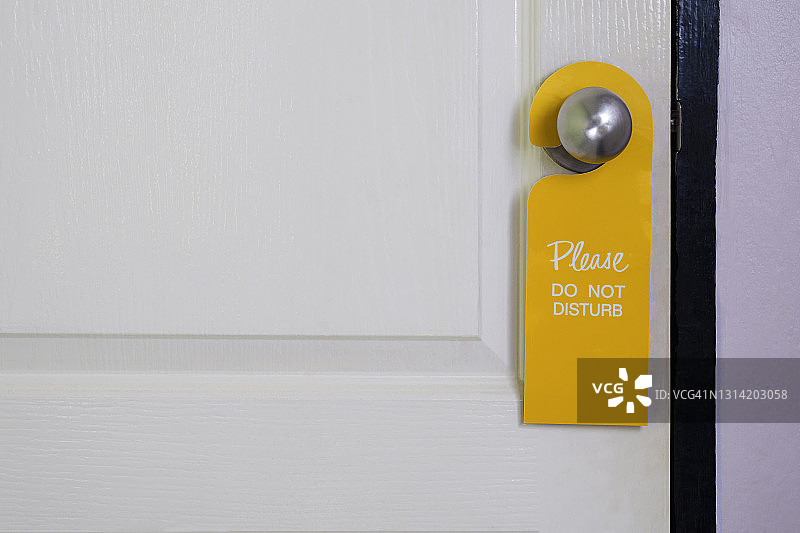 请勿打扰，标牌悬挂在白色木门把手上图片素材