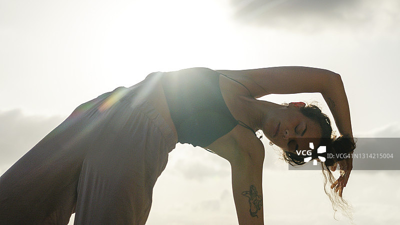 年轻女子在沙滩上练习瑜伽图片素材