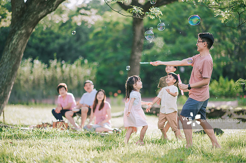 清晨公园里，中国父亲和孩子们玩泡泡棒图片素材