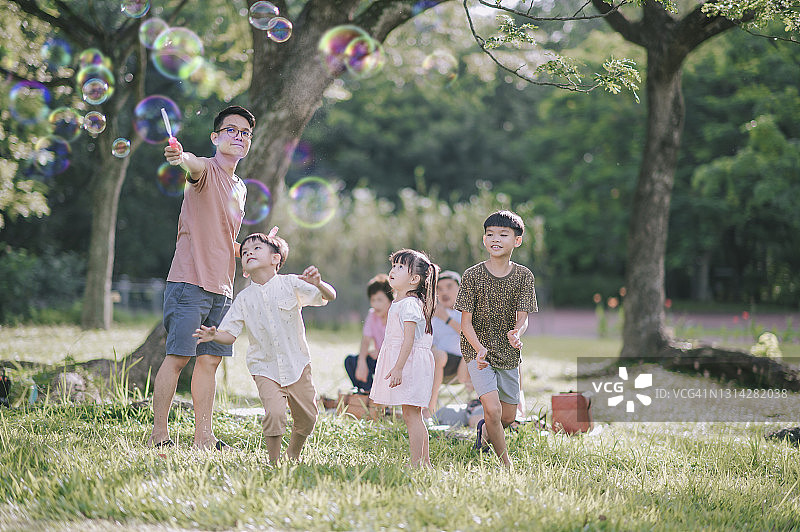 清晨公园里，中国父亲和孩子们玩泡泡棒图片素材