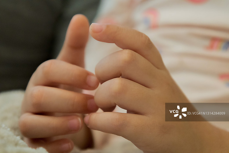 混血幼儿女孩在爸爸读书时摆弄双手图片素材