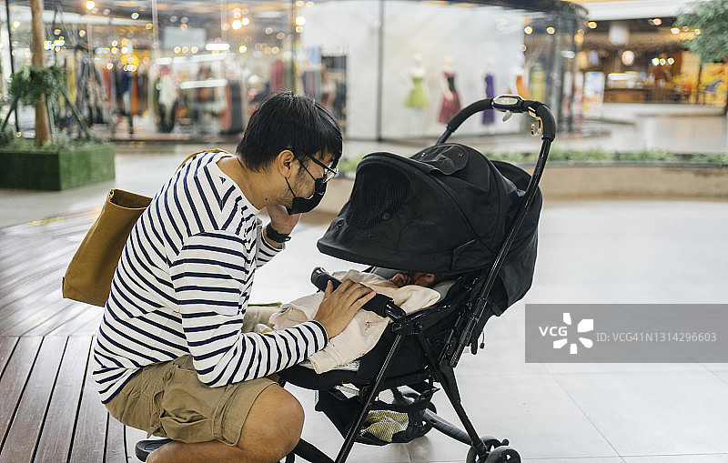新常态下戴口罩的母亲户外照看婴儿图片素材