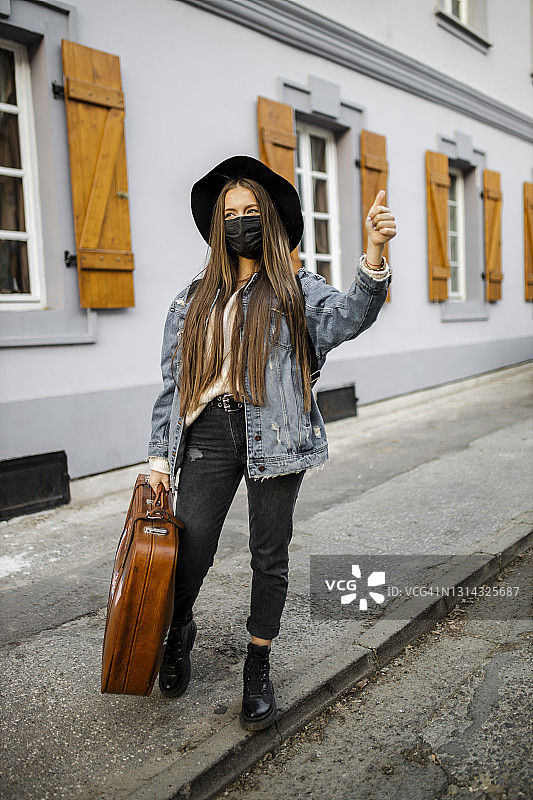 疫情期间，年轻女子携带复古手提箱旅行图片素材