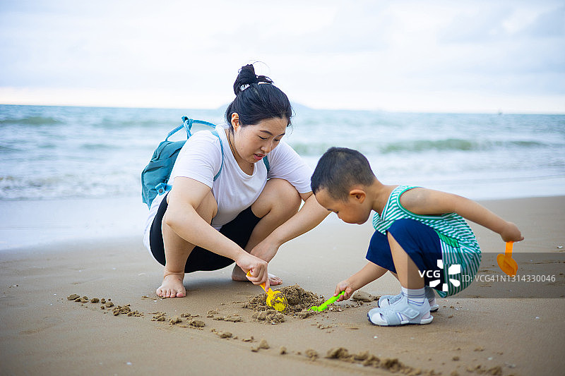 母子在沙滩上玩沙子图片素材