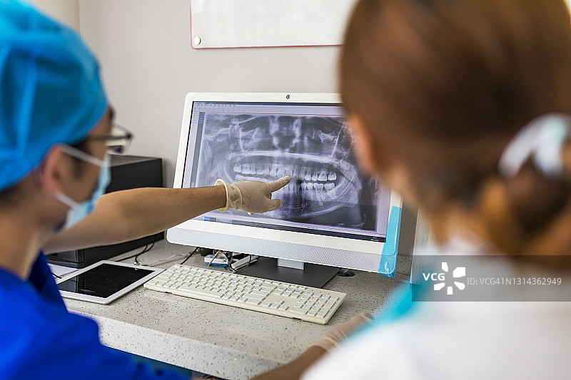 牙医在显示器上向患者展示X光片，计算机诊断牙科断层扫描，在现代牙科诊所规划牙齿治疗图片素材