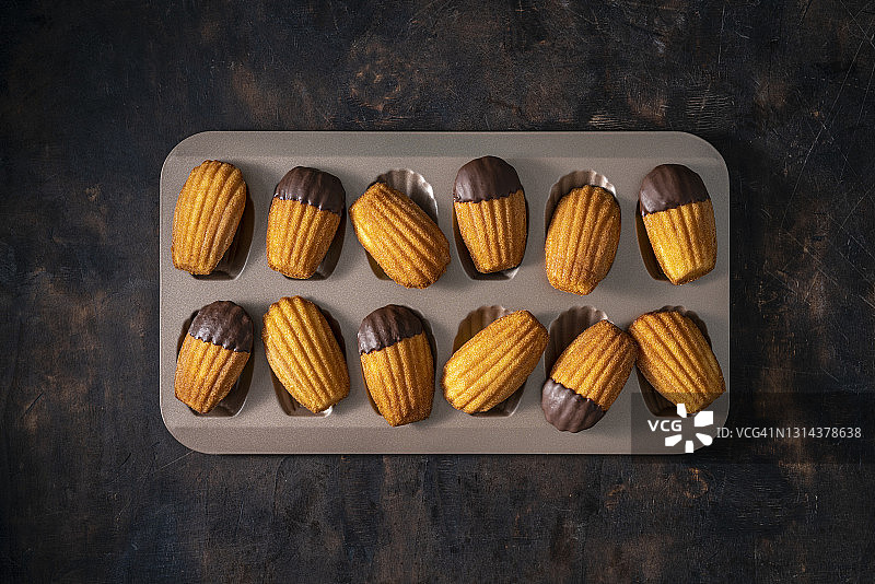 自制玛德琳蛋糕与模具上的融化巧克力图片素材