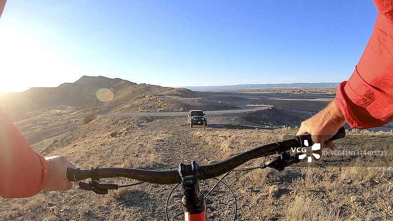 越过山地自行车车把看到的山脉和车辆的视角图片素材