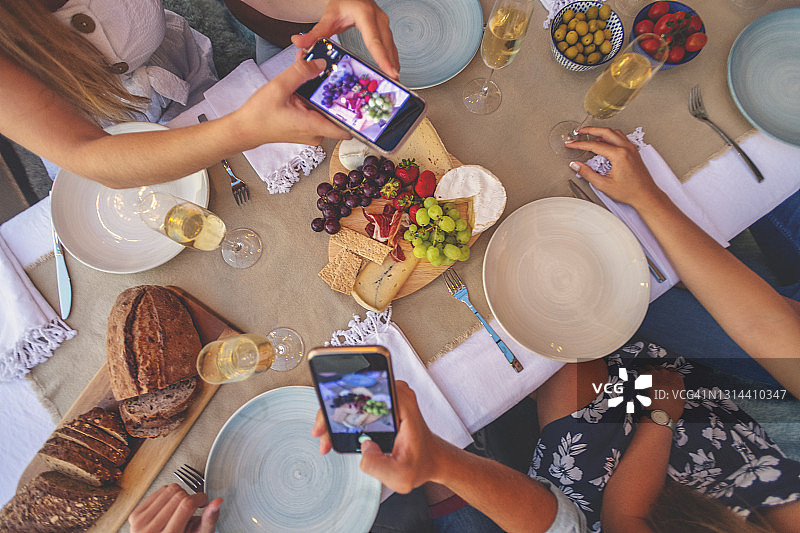 用手机拍摄晚餐派对上的开胃菜和香槟图片素材