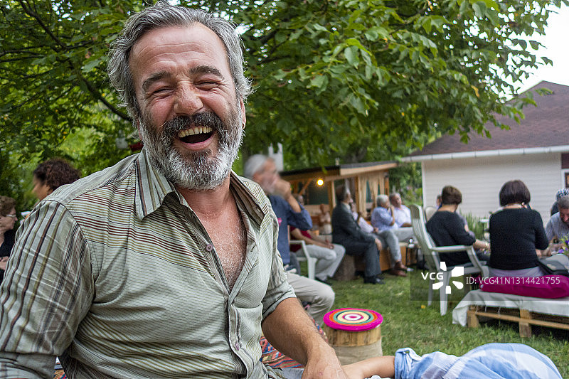 快乐的络腮胡男人坐在花园里图片素材