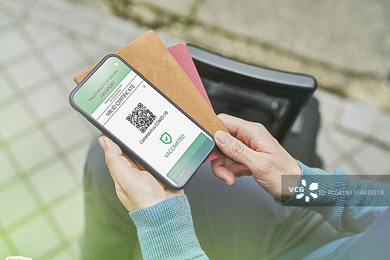 中年女人在户外用智能手机展示电子疫苗护照图片素材