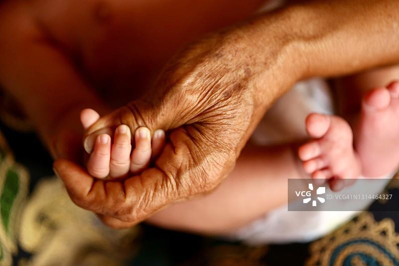 曾祖父的手抓住了曾孙的脚图片素材