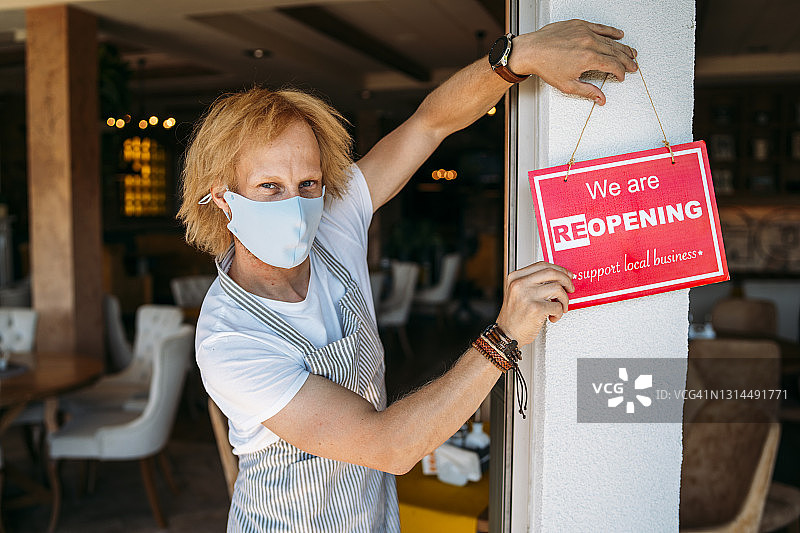 餐厅老板悬挂餐厅开业标志，新冠疫情后重新开业图片素材