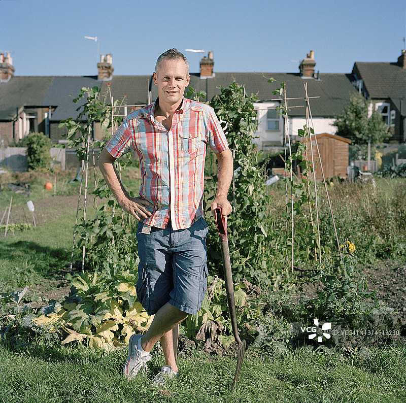 拿着叉子站在菜园里的男人图片素材