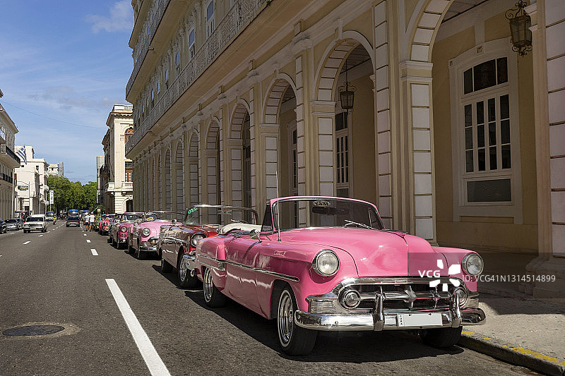 阳光明媚的城市里停放的粉色复古汽车图片素材