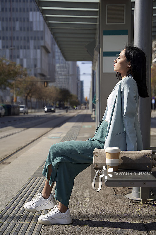在有轨电车站长椅上闭目的女商人图片素材