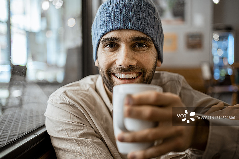 快乐的中年男人在咖啡馆里端着咖啡杯图片素材