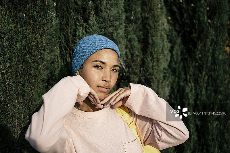 戴着针织帽站在茂盛树叶前的漂亮女人图片素材