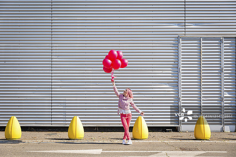 身穿粉色夹克的女人在路上看气球图片素材