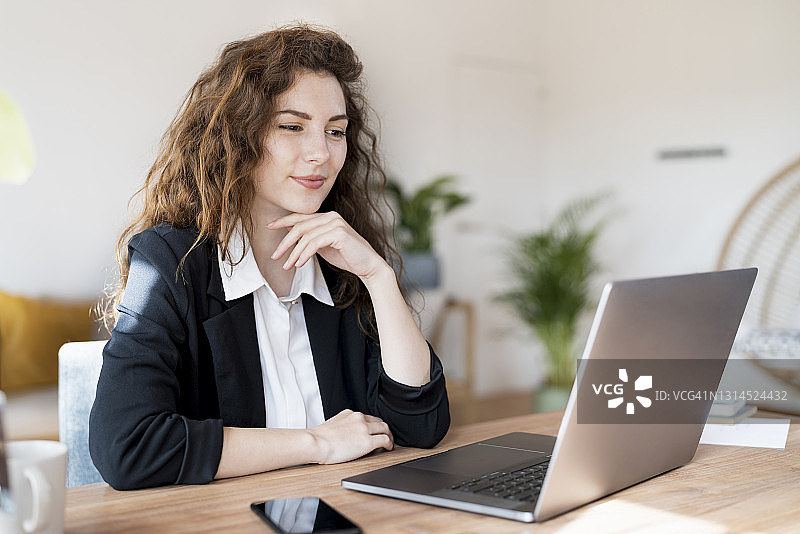 女商人手托下巴在家用笔记本电脑图片素材