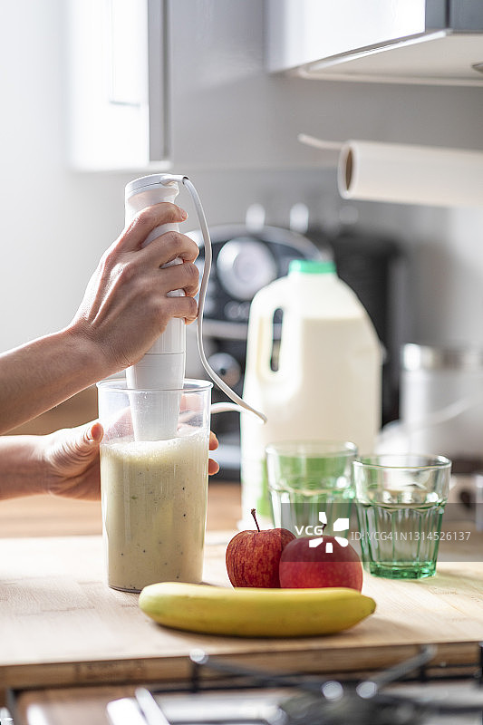 在家用电动搅拌机准备水果奶昔的妇女图片素材