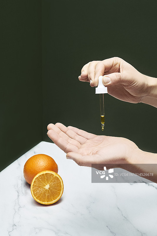 年轻女子将精华液滴在手上图片素材