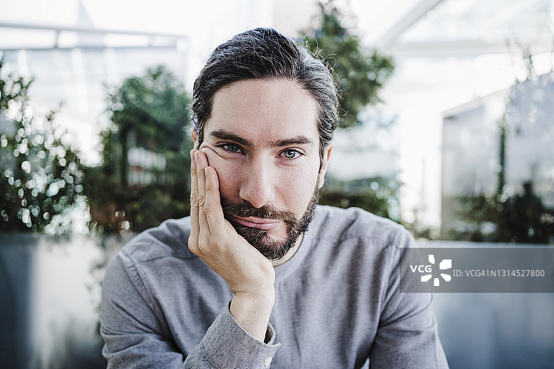 办公室里托着下巴、有着灰色眼睛的男商人图片素材