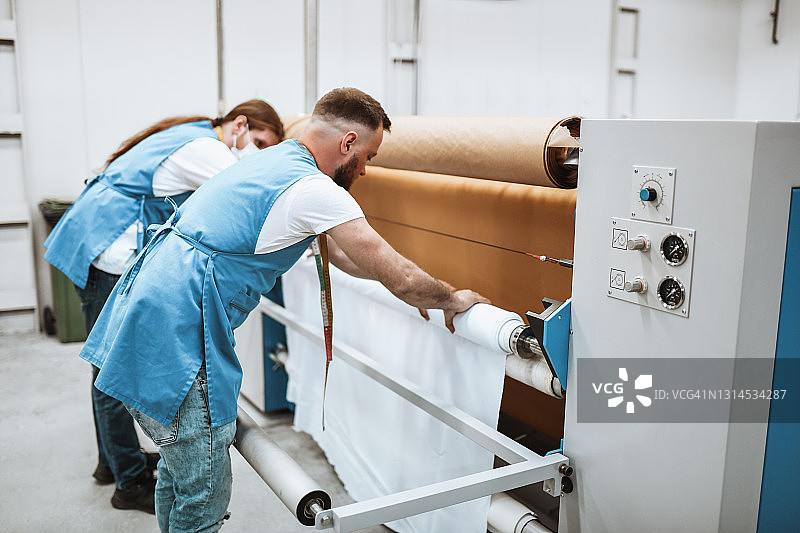 纺织厂工人用服装印花机轧制材料图片素材