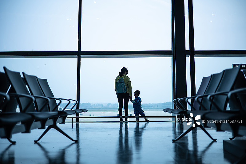 母亲和儿子在机场窗口向外看图片素材