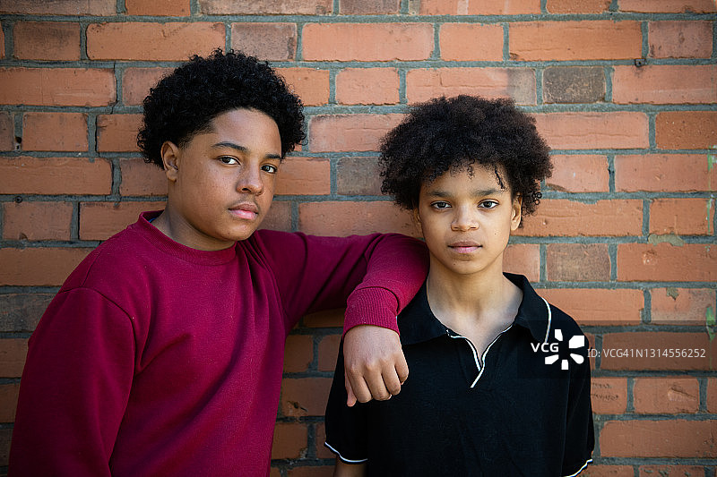 靠在砖墙上的青少年兄弟图片素材