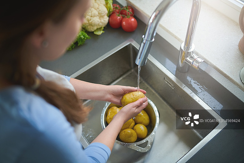 女人在家厨房水槽冲洗土豆图片素材