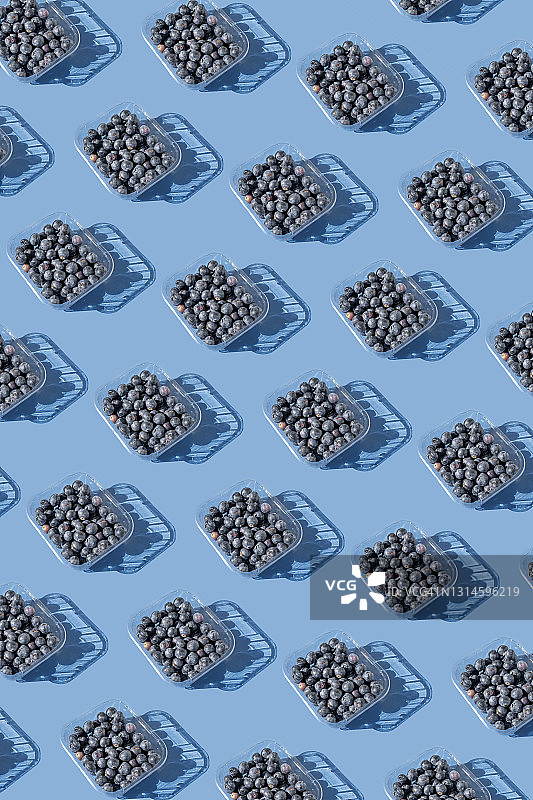 蓝色背景上的塑料包装蓝莓图片素材