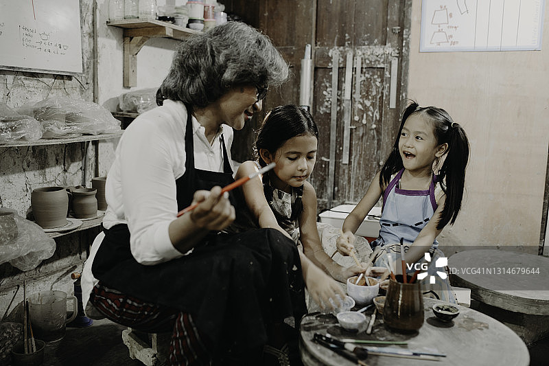 年长的女人在她的工作室里教她的孙子如何制作陶器图片素材