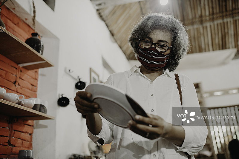 正在查看泥塑产品的老年女人图片素材