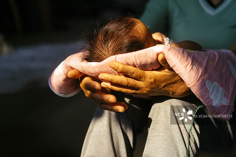 祖母抱着1个月大的宝宝在家晒太阳治疗黄疸图片素材
