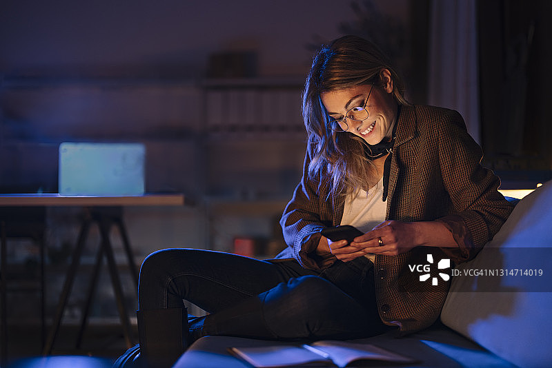 夜晚用智能手机聊天的欢笑女士图片素材