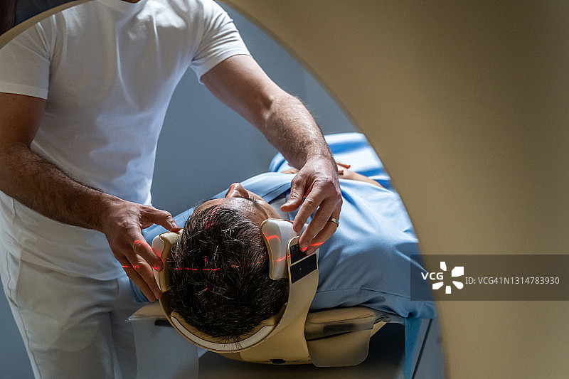 医生在MRI扫描前固定男性患者的头部图片素材