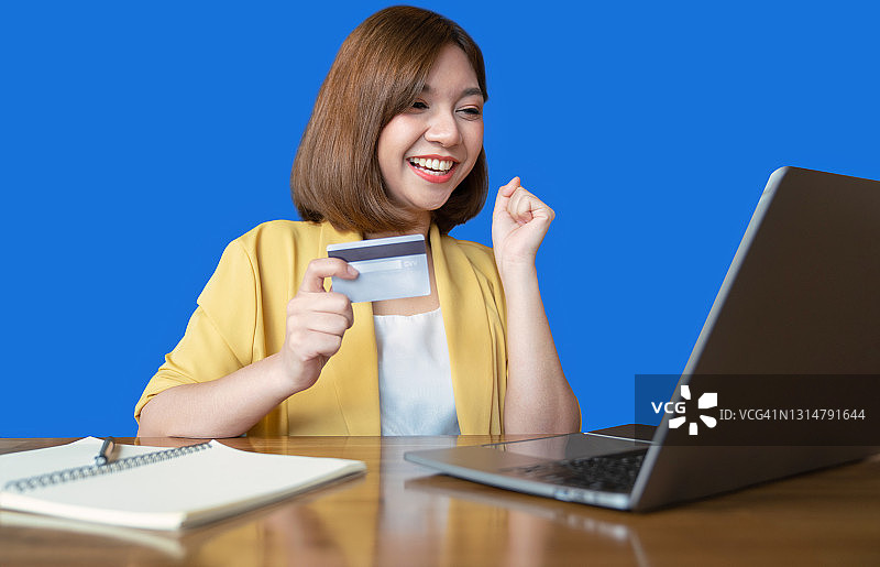 年轻女人拿着信用卡使用笔记本电脑。女商人或企业家工作。网上购物。电子商务。网上银行。消费概念图片素材