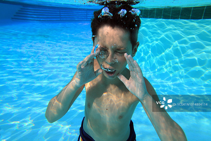青少年男孩在游泳池中的水下肖像特写图片素材
