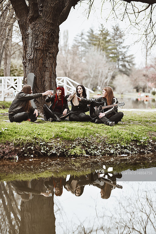 哥特人在公园里弹着吉他、听着音乐、喝着饮料野餐图片素材