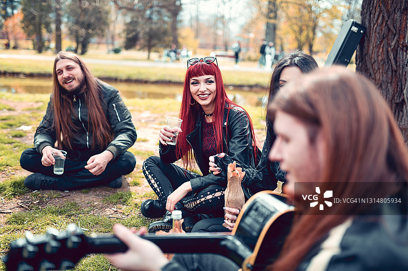 金属党朋友在公园野餐时享用饮料和听音乐图片素材