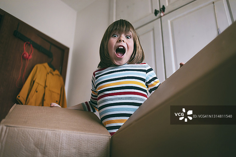 在家打开快递盒的快乐男孩图片素材