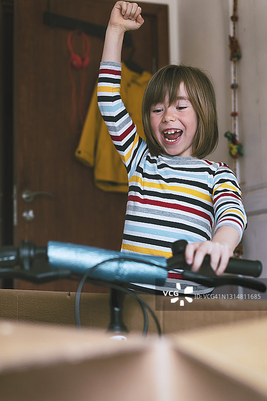 快乐男孩在网上购物后拆开新自行车图片素材